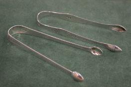 TWO GEORGE III BRIGHT CUT SUGAR TONGS. London 1791, maker W C & 1794, maker Peter and Ann Bateman.