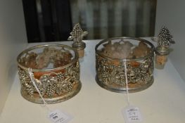 A pair of decorative bottle coasters and stoppers.