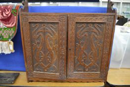 A small carved oak hanging cupboard.