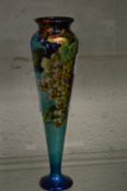 An enamelled copper tapering vase decorated with bunches of grapes, signed Limoges.