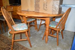 A modern pine drop flap kitchen table and four chairs.