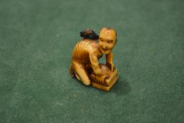 An unusual Japanese carved ivory okimono or netsuke of a crouching man.