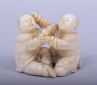 A JAPANESE MEIJI PERIOD CARVED IVORY NETSUKE - KARAKO, the two boys seated whilst playing, one