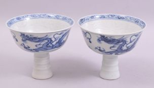 A GOOD PAIR OF CHINESE BLUE AND WHITE PORCELAIN STEM CUPS, painted with dragons, the interior with