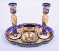 A BLUE AND GILT GLASS FIVE PIECE DESK SET, comprising a pair of candlesticks, 15cm high, circular