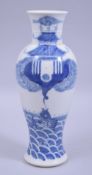 A CHINESE BLUE AND WHITE PORCELAIN VASE, painted with a carp amongst stylised waves and a temple,