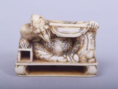 A JAPANESE MEIJI PERIOD CARVED IVORY NETSUKE - RECUMBENT WARRIOR, the warrior lead aside on a low