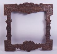 A GOOD LARGE CHINESE CARVED HARDWOOD FRAME, carved with dragons, phoenix, bats and emblems, the