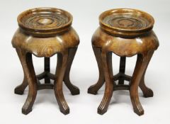 A PAIR OF CHINESE OAK CIRCULAR STANDS with turned, dished tops, supported on five curving legs