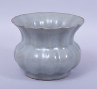 A CHINESE CELADON CRACKLE GLAZE RIBBED SQUAT VASE, the base with incised calligraphy, 11cm high.