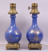 A PAIR OF CHINESE BLUE GROUND AND GILT DECORATED PORCELAIN LAMPS / VASES with ormolu mounts, the