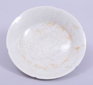 A SMALL CHINESE CELADON GLAZED POTTERY DISH, the centre with incised decoration, 15cm diameter.