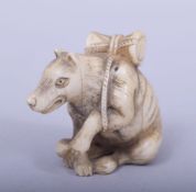 A JAPANESE MEIJI PERIOD CARVED IVORY NETSUKE - KITSUNE, the fox in a seated position with a drum on