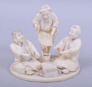 A JAPANESE MEIJI PERIOD CARVED IVORY OKIMONO GROUP, depicting three figures around grain, one