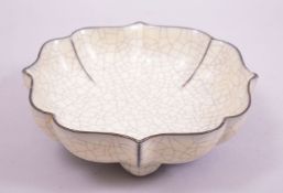 A CHINESE CRACKLE GLAZE FOLIATE SHAPED BOWL, supported on four feet with incised calligraphy to