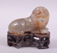 A CHINESE AGATE FIGURE OF A LION DOG, on a fitted wooden stand, figure 8cm long.