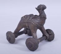 AN ISLAMIC BRONZE MODEL OF A CAMEL ON WHEELS, 11cm wide.