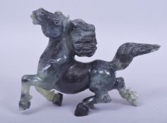 A CARVED JADE / JADEITE MODEL OF A HORSE, 16cm wide.