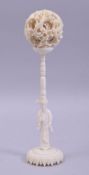A CHINESE 19TH CENTURY CARVED IVORY PUZZLE BALL AND STAND, the ball carved with dragons, the stand