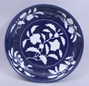 A LARGE CHINESE BLUE GLAZED PORCELAIN DISH, with white glazed floral decoration, 30.5cm diameter.