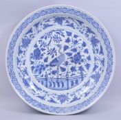 A LARGE CHINESE BLUE AND WHITE PORCELAIN CHARGER, central painted with a peacock amongst native