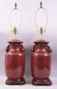 A GOOD LARGE PAIR OF CHINESE SANG DE BOEUF TWIN HANDLE LAMP VASES, the handles formed in the shape