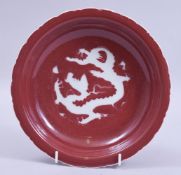 A CHINESE MING STYLE COPPER RED GLAZED PETAL FORM DISH, the centre decorated with white dragon, with