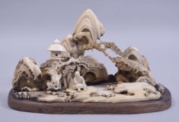 A CHINESE CARVED IVORY / BONE LANDSCAPE GROUP, depicting a man seated beside a lantern in a rocky