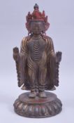 A CHINESE GILT AND RED PAINTED BRONZE DEITY, stood upon a circular base, 33cm high.