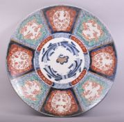 A LARGE JAPANESE IMARI PORCELAIN CHARGER, painted with floral panels in the imari pallette, the
