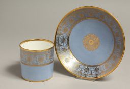 A SEVRES COFFEE CAN AND SAUCER decorated with elaborate classical gilding on a light blue ground.