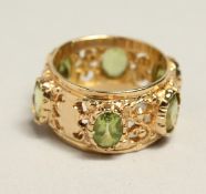 A 14CT GOLD PERIDOT BAND RING.