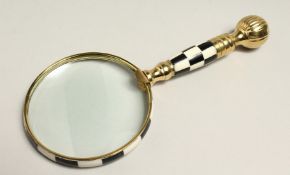 A MAGNIFYING GLASS WITH CHECKERED AND BRASS HANDLE.