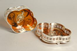 A PAIR OF SILVER PLATE AND FAUX TORTOISESHELL QUATREFOIL WINE COASTERS.