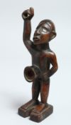 A CARVED WOOD TRIBAL FIGURE with glass eyes 7ins long