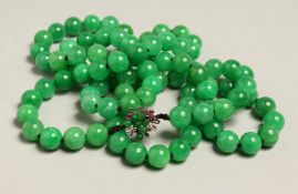 A VERY GOOD LONG JADE NECKLACE with .585 gold and ruby clasp. 44ins long.