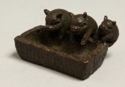 THREE JAPANESE BRONZE PIGS at a trough. 1.75ins