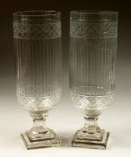 A PAIR OF SLICE CUT GLASS STORM LAMPS on stepped bases. 13ins high.