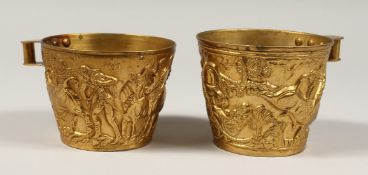 AFTER THE ANTIQUE. A PAIR OF GREEK TWO HANDLED GILT CUPS. 4ins diameter.