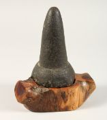 AN EARLY HAWAIIAN STONE POUNDER 7ins high on a wooden base.