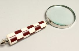 A MAGNIFYING GLASS WITH RED CHECKERED HANDLE.