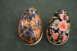Two painted papier mache eggs on stands.