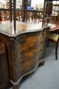A serpentine fronted walnut chest of drawers with brushing slide.