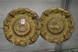 A pair of gilded cast pewter plates depicting swans.