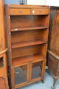 A mahogany bookshelf with two small drawers and a pair of glazed doors.