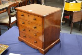 A mahogany table top four drawer chest.