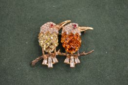 A silver brilliant set brooch of two birds on a branch.
