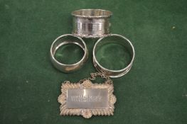Three silver napkin rings and a wine label.