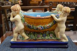 A Majolica style jardiniere modelled as a basket being held by four cherubs.
