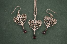 A silver chain and earrings set with garnets.
